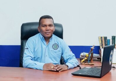 Gerente de Transguamuez S.A., Adrian Felipe Ruano Gomez, sentado en su escritorio de oficina con camisa corporativa azul y logo de la empresa.